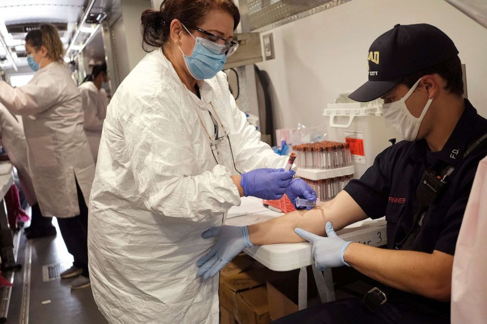 PHOTO: Jersey City firefighter Matt Finnerty, right, has blood drawn to test for coronavirus antibodies at a testing site in Jersey City, N.J., May 4, 2020.