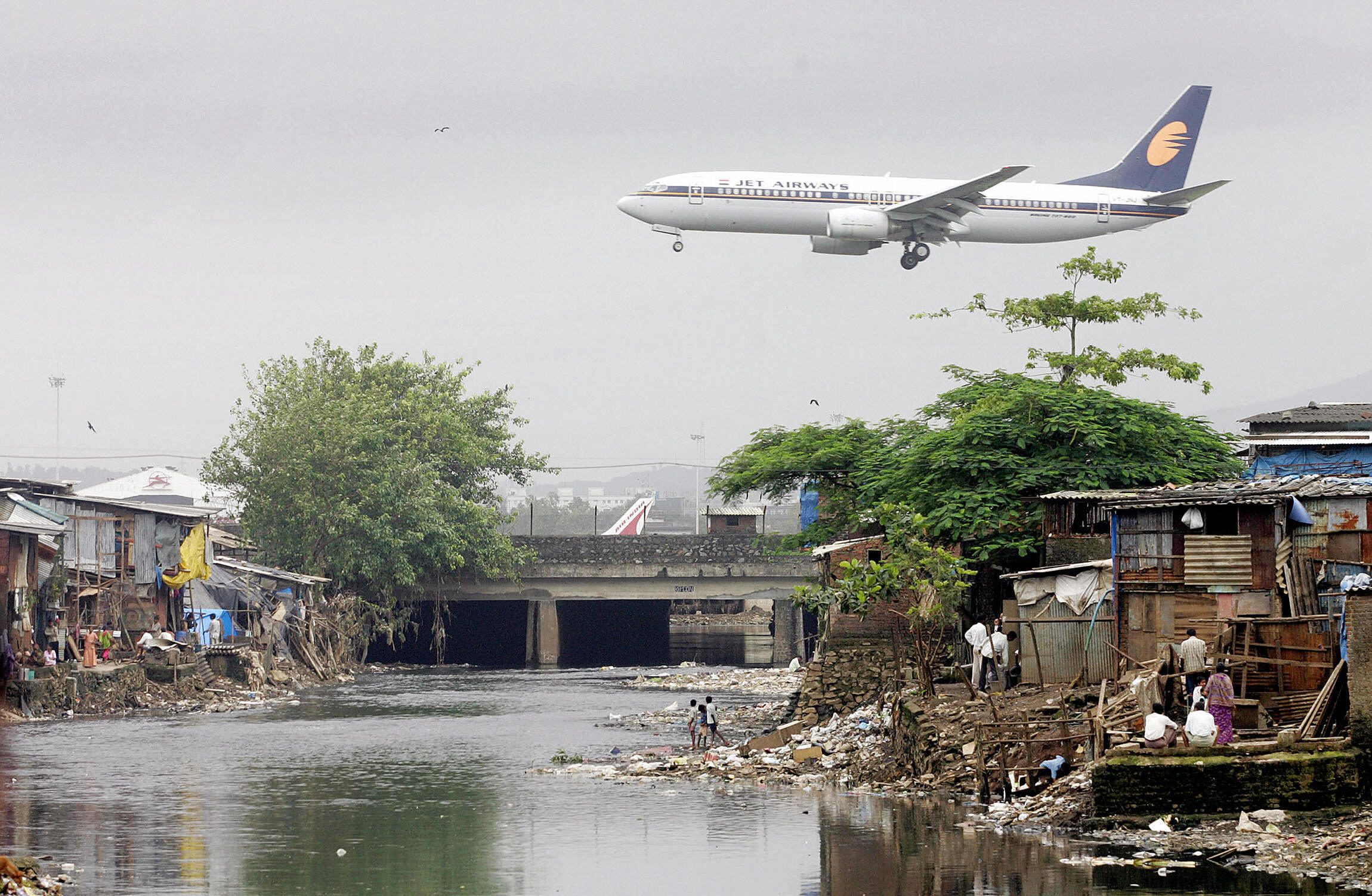 PHOTO: A Jet Airways plane flies over the Mithi River on its way to landing at Mumbai airport, at Bharat Nagar, Aug. 16, 2005 in Hyderabad, India.  