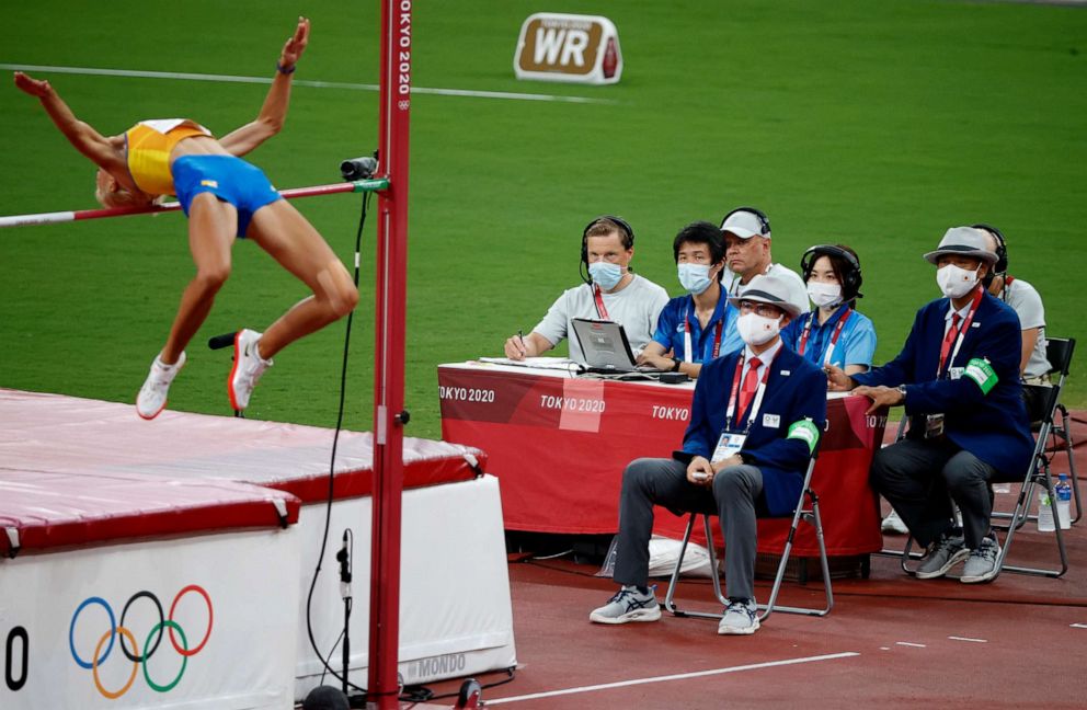 PHOTO: Officials in protective face mask watch Yuliya Levchenko of Ukraine in action during the women's high jump in Aug. 7, 2021, in Tokyo, Japan.