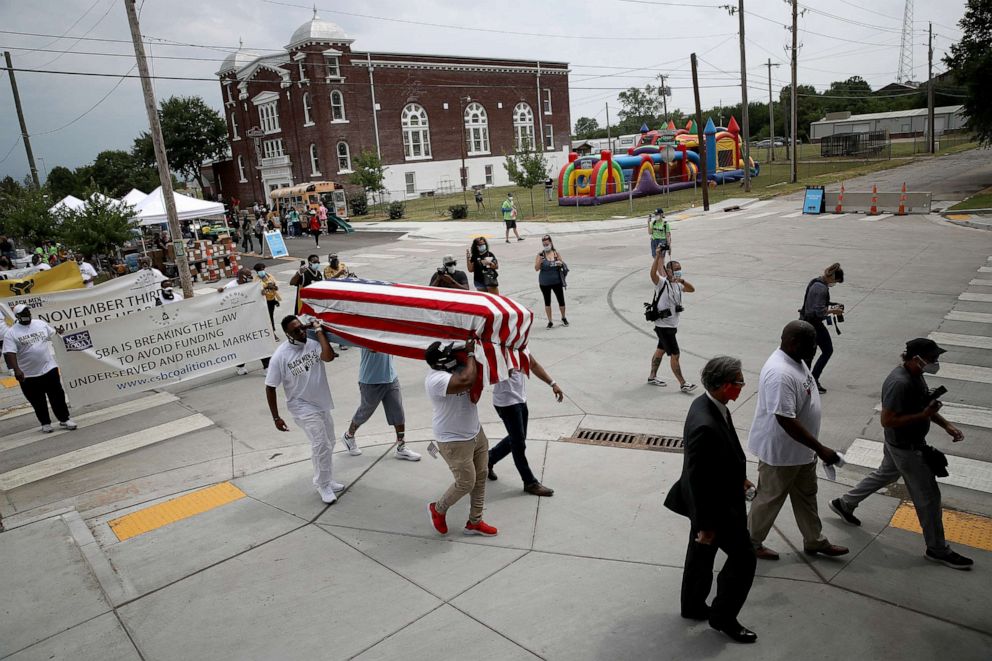 PHOTO: People carry an empty casket draped with an American flag to symbolize the destruction of Tulsa's Black Wall Street in 1921 during a Juneteenth march and celebration in the Greenwood District of the city, June 19, 2020, in Tulsa, Okla.