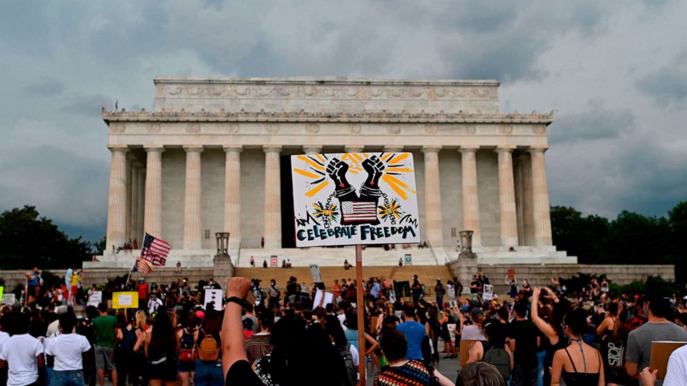 PHOTO: Demonstrators hold signs as they take part in a Juneteenth march and rally in front of the Lincoln Memorial, in Washington, June 19, 2020.