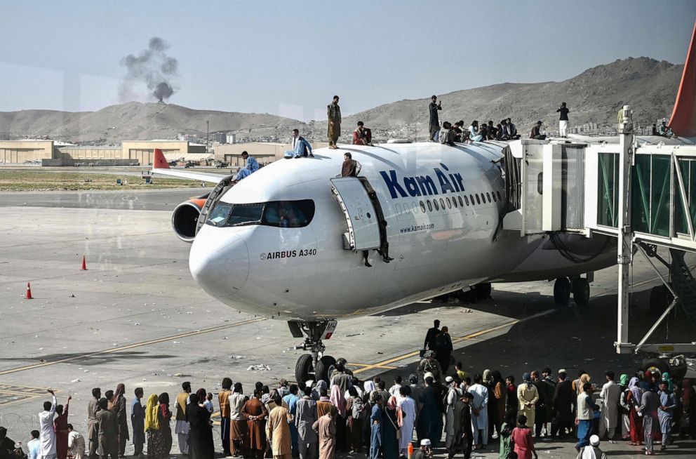PHOTO: Afghan people climb atop a plane as they wait at the Kabul airport in Afghanistan on Aug. 16, 2021, as thousands of people mobbed the city's airport trying to flee the Taliban's feared hardline brand of Islamist rule.