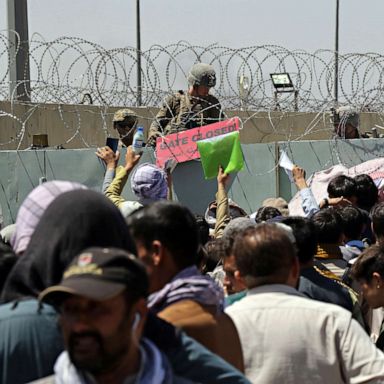 PHOTO: A U.S. soldier holds a sign indicating a gate is closed as hundreds of people gather, some holding documents, near an evacuation control checkpoint on the perimeter of the Hamid Karzai International Airport, in Kabul, Aug. 26, 2021.