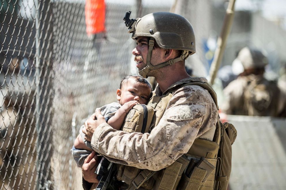 PHOTO: A Marine with Special Purpose Marine Air-Ground Task Force-Crisis Response-Central Command calms a child during an evacuation at Hamid Karzai International Airport in Kabul, Afghanistan, Aug. 26, 2021.