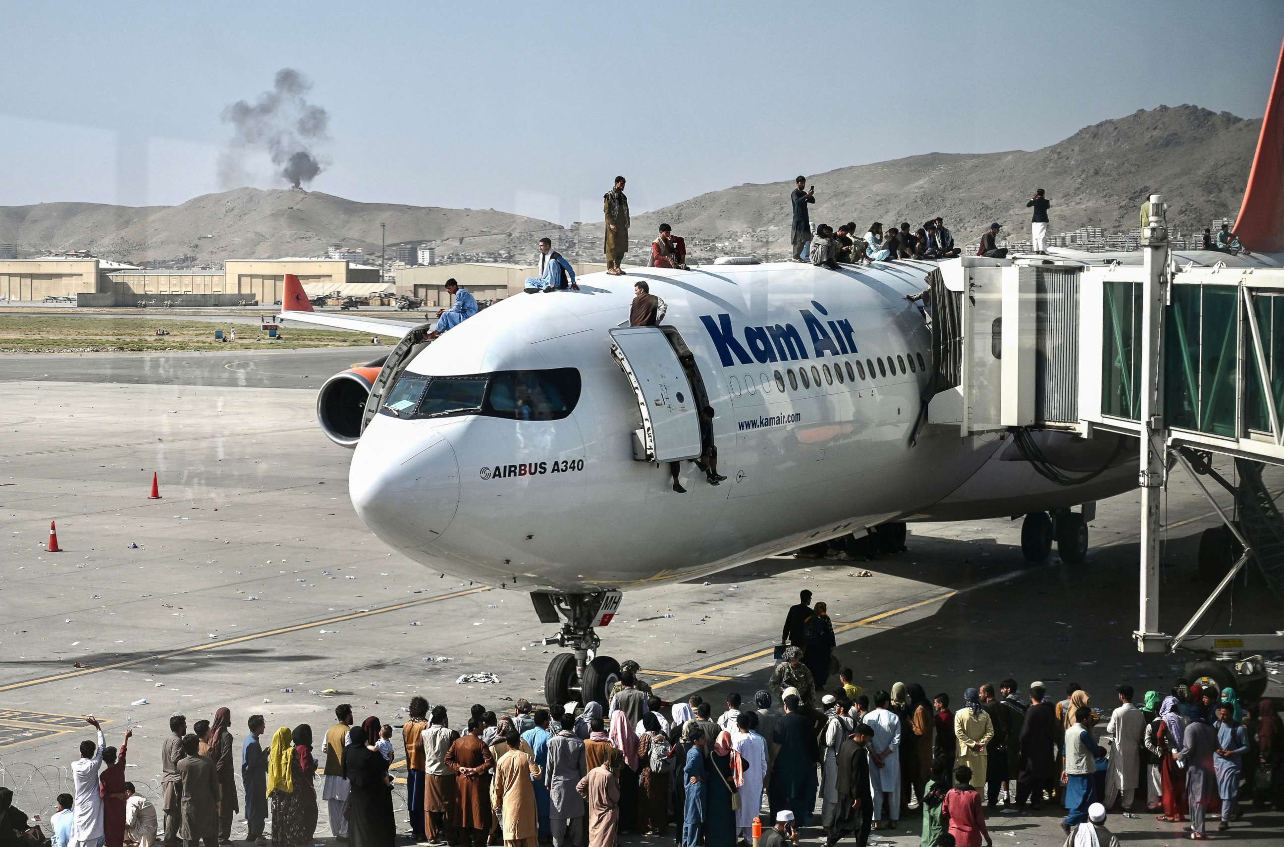 PHOTO: Afghan people climb atop a plane as they wait at the Kabul airport in Kabul, Aug. 16, 2021.