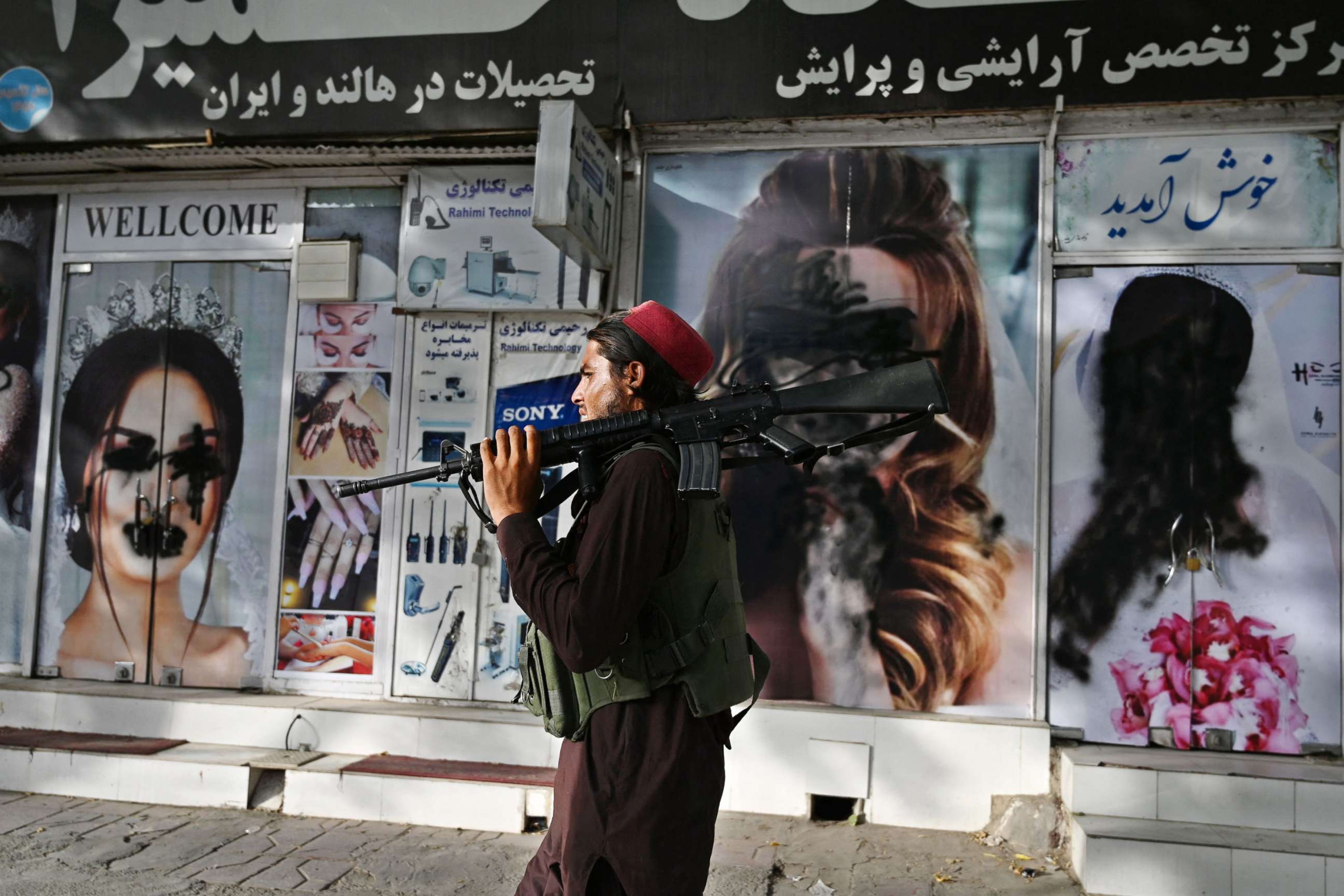 PHOTO: A Taliban fighter walks past a beauty salon with images of women defaced using a spray paint in Shar-e-Naw in Kabul, Afghanistan, Aug. 18, 2021.
