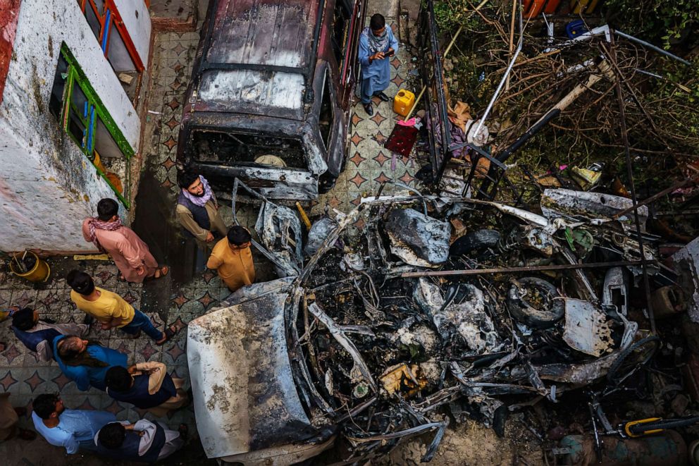 PHOTO: Relatives and neighbors of the Ahmadi family gathered around the incinerated husk of a vehicle targeted and hit earlier Sunday afternoon by an American drone strike, in Kabul, Afghanistan,  Aug. 30, 2021.