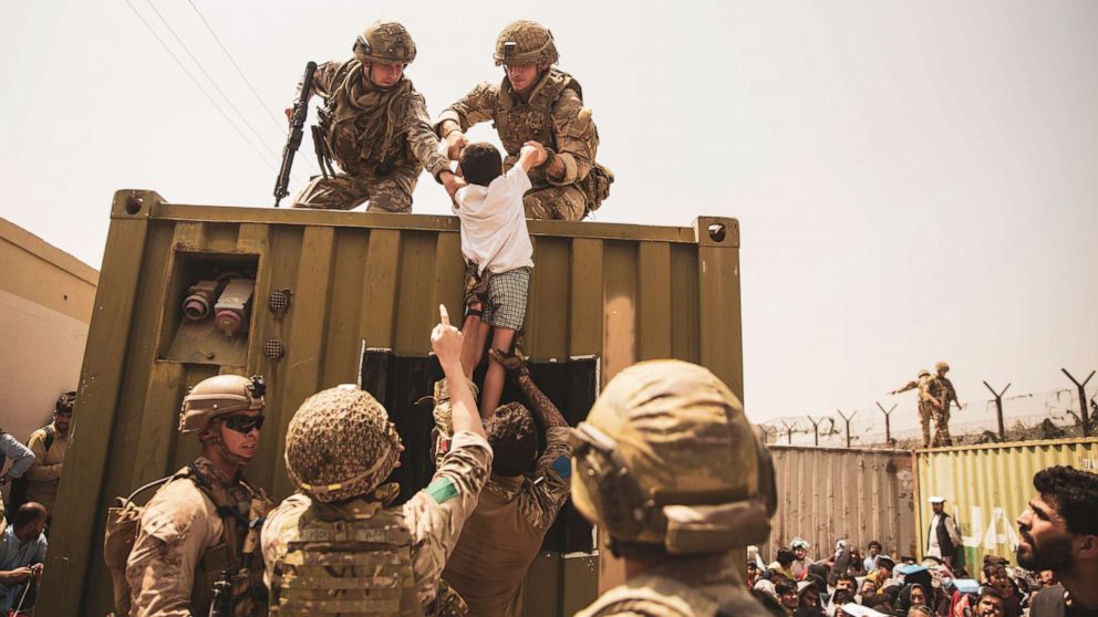 PHOTO: UK coalition forces, Turkish coalition forces, and U.S. Marines assist a child during an evacuation at Hamid Karzai International Airport, Kabul, Afghanistan, Aug. 20, 2021.