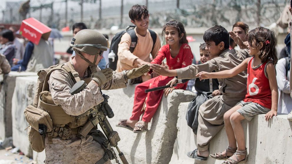 PHOTO: A Marine plays with children waiting to process during an evacuation at Hamid Karzai International Airport, Kabul, Afghanistan, Aug. 20, 2021.