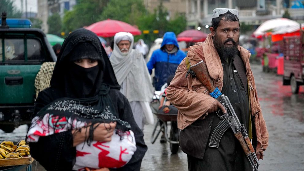 PHOTO: A Taliban fighter stands guard as people walk through the old market, in the city of Kabul, Afghanistan, on May 3, 2022.