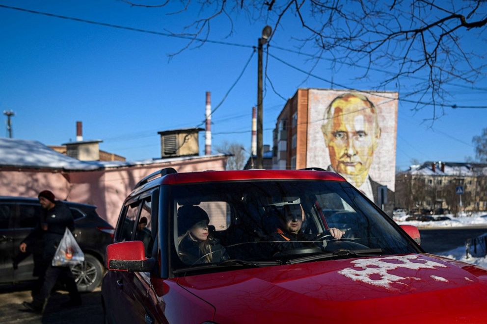 PHOTO: People ride in a car near a mural of Russian President Vladimir Putin on a residential building in the town of Kashira, south of Moscow, on Feb. 23, 2023.