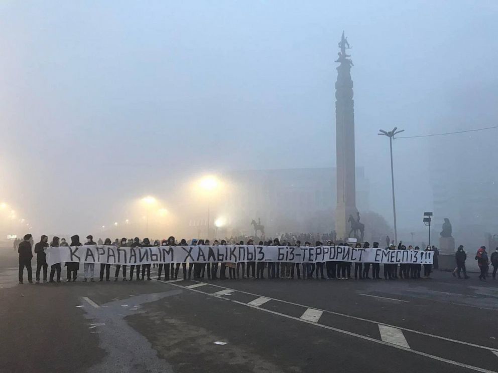 PHOTO: Protesters hold a long banner which reads, "We are the people, not terrorists" at the Republic Square in Kazakhstan's largest city, Almaty, Jan 7, 2022, as protests over a hike in energy prices spun out of control. 