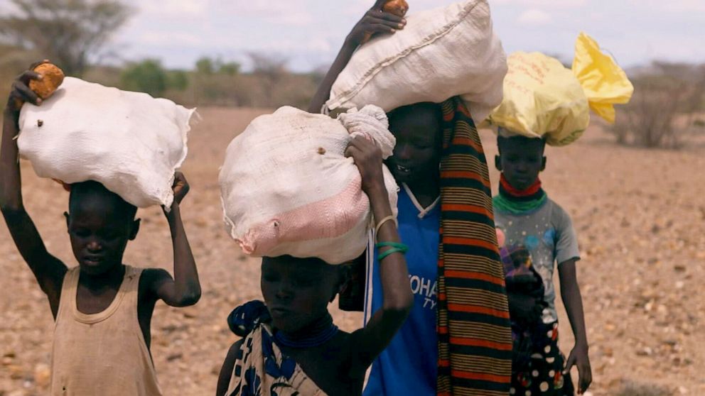 PHOTO: Ekiru, center, and other children carry sacks of palm fruit atop their heads in rural Turkana County, northwestern Kenya, in May 2022.