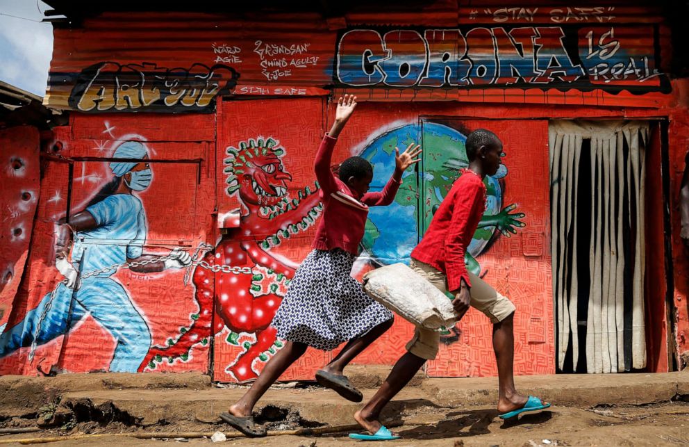 PHOTO: Children run down a street past an informational mural warning people about the dangers of coronavirus in the Kibera slum of Nairobi, Kenya, June 3, 2020.