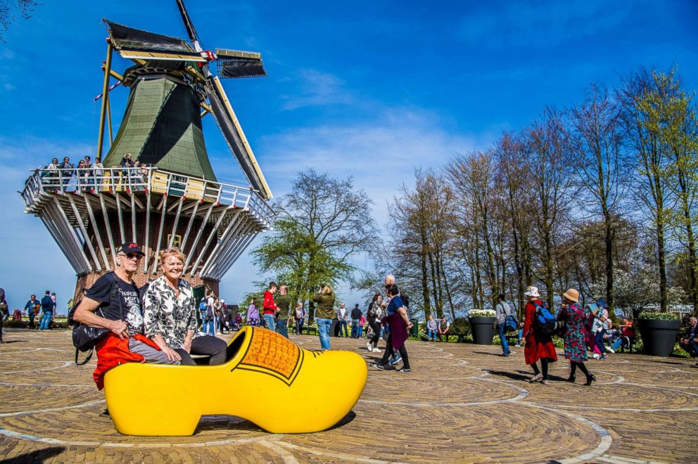 PHOTO: Visitors sit in a wooden shoe behind a windmill at the Keukenhof gardens, April 17, 2018, in Lisse, The Netherlands.