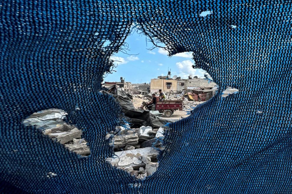 PHOTO: Palestinians, seen through a torn tent, ride a motorized vehicle past the rubble, amid the Israel-Hamas conflict, in Khan Younis, in the southern Gaza Strip, September 16, 2024.