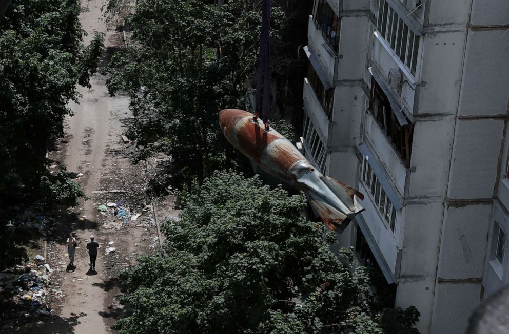 PHOTO: People watch as a defused 500kg bomb that did not detonate when it landed on an apartment building in March, is lowered from the roof by members of a specialized team in the Saltivka neighborhood in Kharkiv, Ukraine, June 23, 2022.
