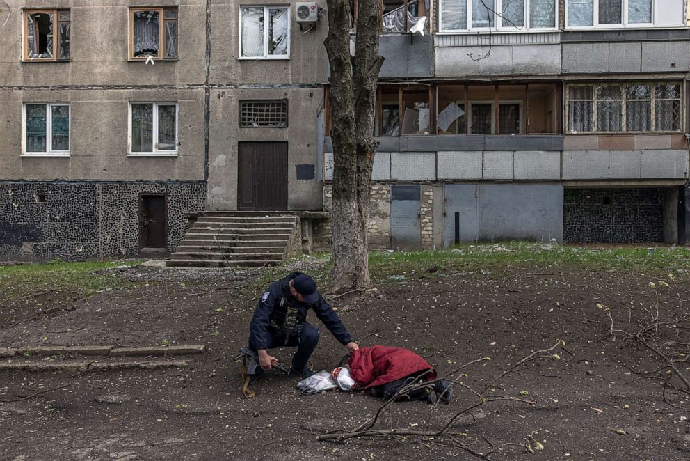 PHOTO: A police officer checks the pulse of a civilian who was killed in a residential area hit by the Russian artillery shelling, in Kharkiv, northeast Ukraine, April 19, 2022.