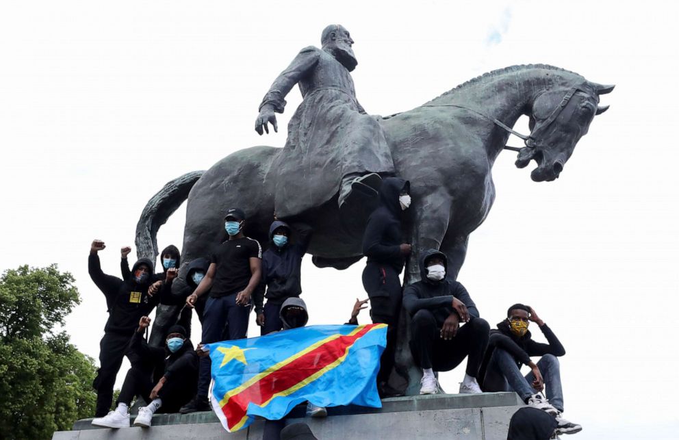 PHOTO: Demonstrators stand on the statue of Leopold II as one of them holds a national flag of the Democratic Republic of Congo during a protest in central Brussels, Belgium June 7, 2020.