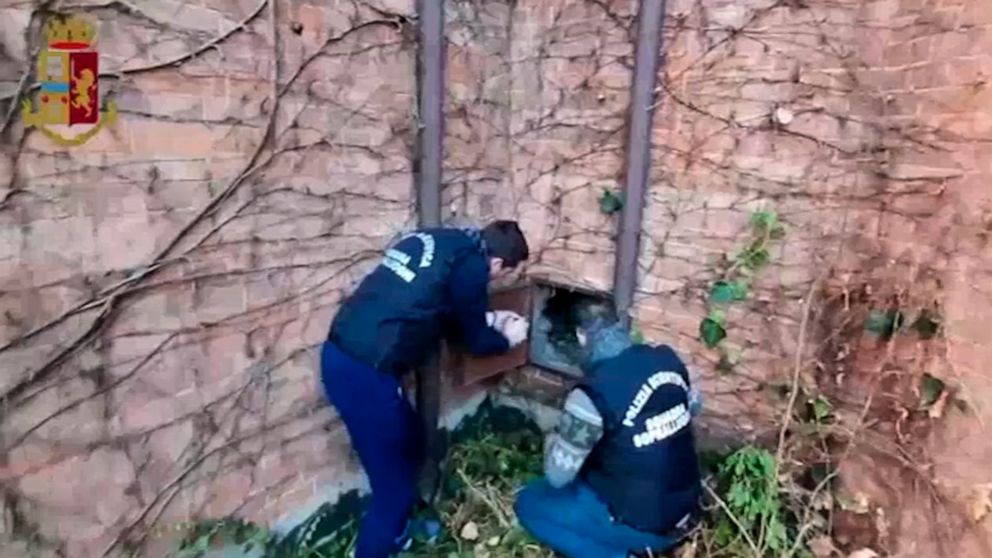 PHOTO: This image taken from a video distributed Wednesday, Dec. 11, 2019 by Italian police shows two forensic police officers approaching a metal panel in which a painting was found, in Piacenza, northern Italy.