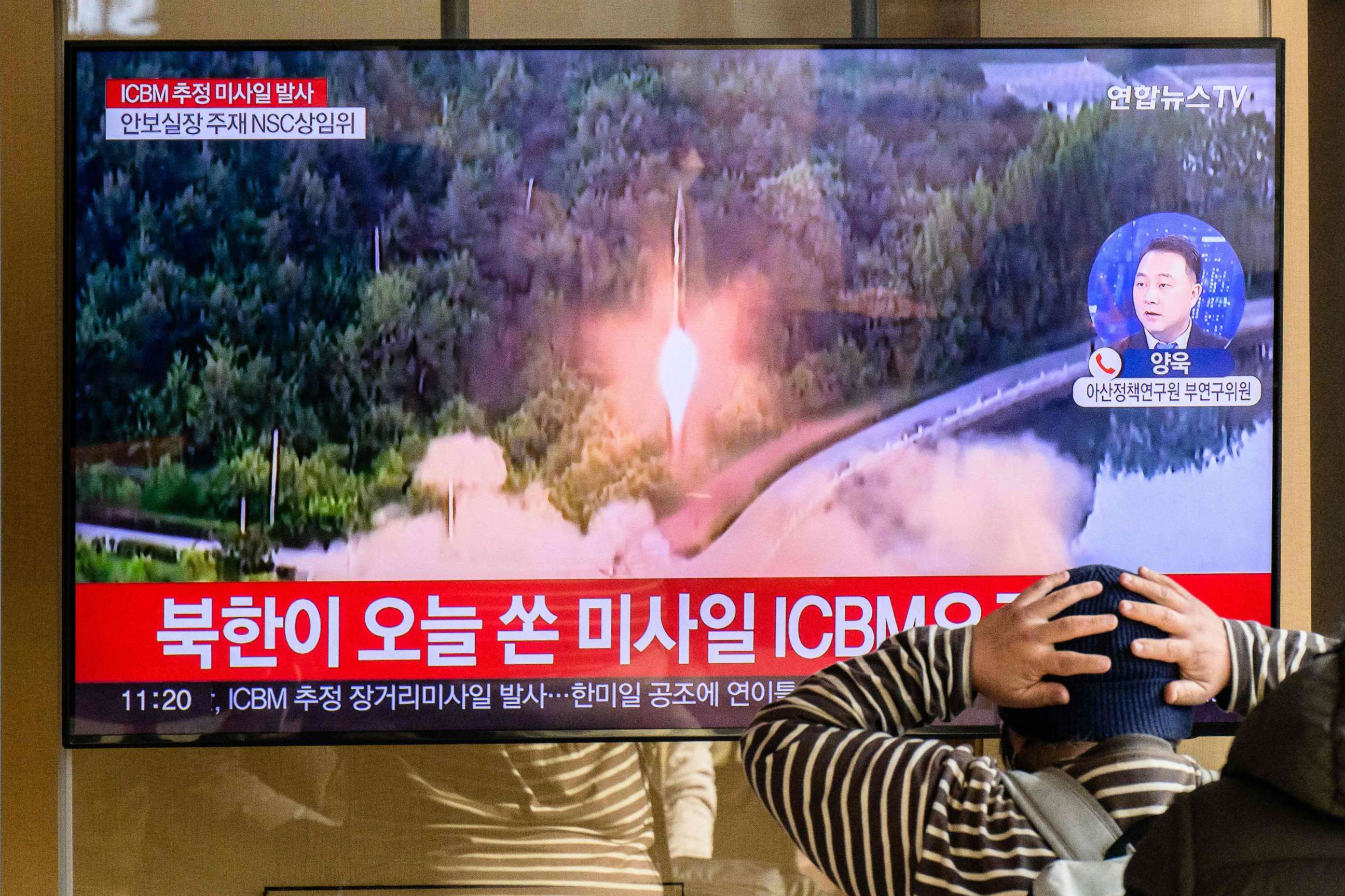 PHOTO: TOPSHOT - A man watches a television showing a news broadcast with file footage of a North Korean missile test, at a railway station in Seoul on November 18, 2022.