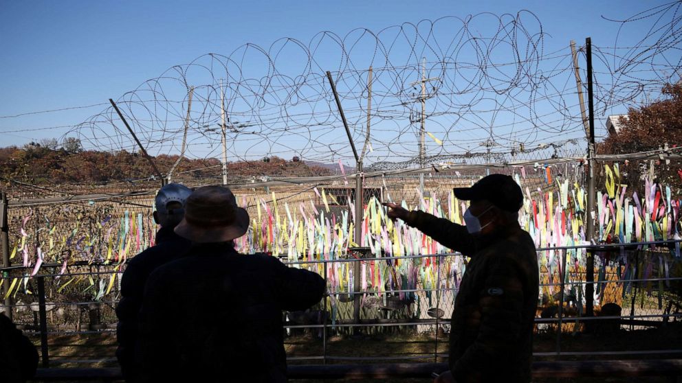 PHOTO: Men look at a military fence decorated with ribbons bearing messages wishing for the reunification of the two Koreas near the demilitarized zone separating the two Koreas, in Paju, South Korea, November 4, 2022.    