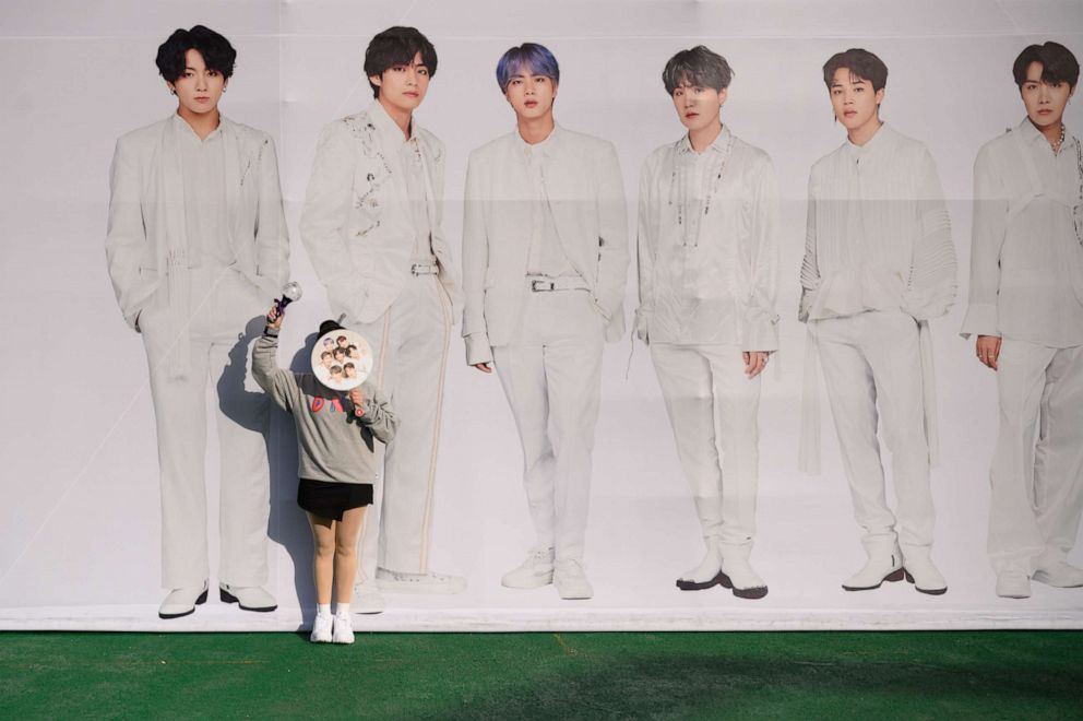 PHOTO: In this Oct. 29, 2019, photo, a fan of South Korea's BTS K-pop group poses against a backdrop featuring an image of the band members as they arrive for the final concert of their world tour at the Olympic stadium in Seoul.