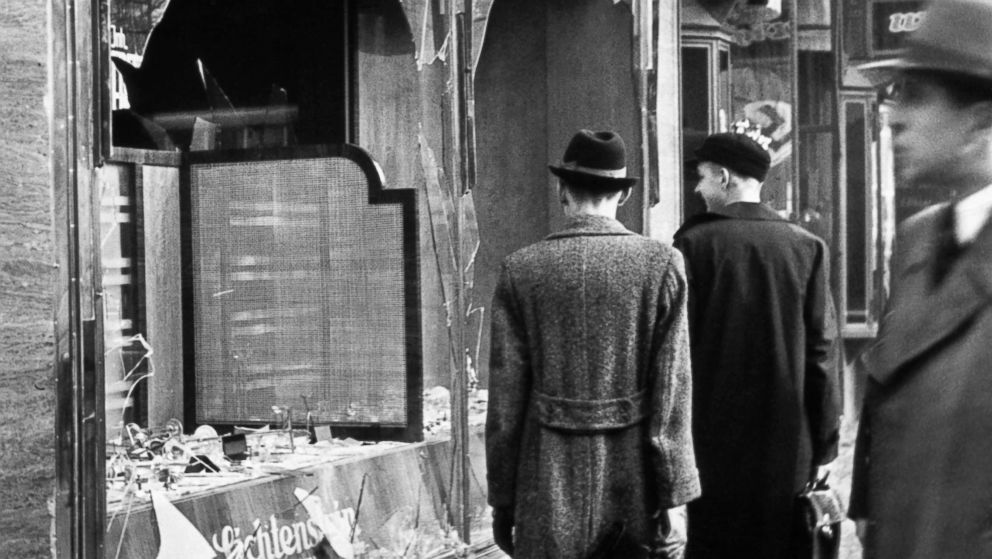 PHOTO: Pedestrians look at the broken windows of a Jewish-owned shop targeted by Nazis on the evening of Kristallnacht in Germany, 1938.