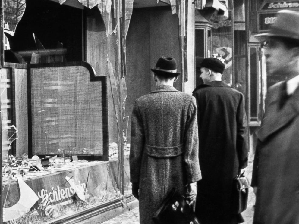 PHOTO: Pedestrians look at the broken windows of a Jewish-owned shop targeted by Nazis on the evening of Kristallnacht in Germany, 1938.