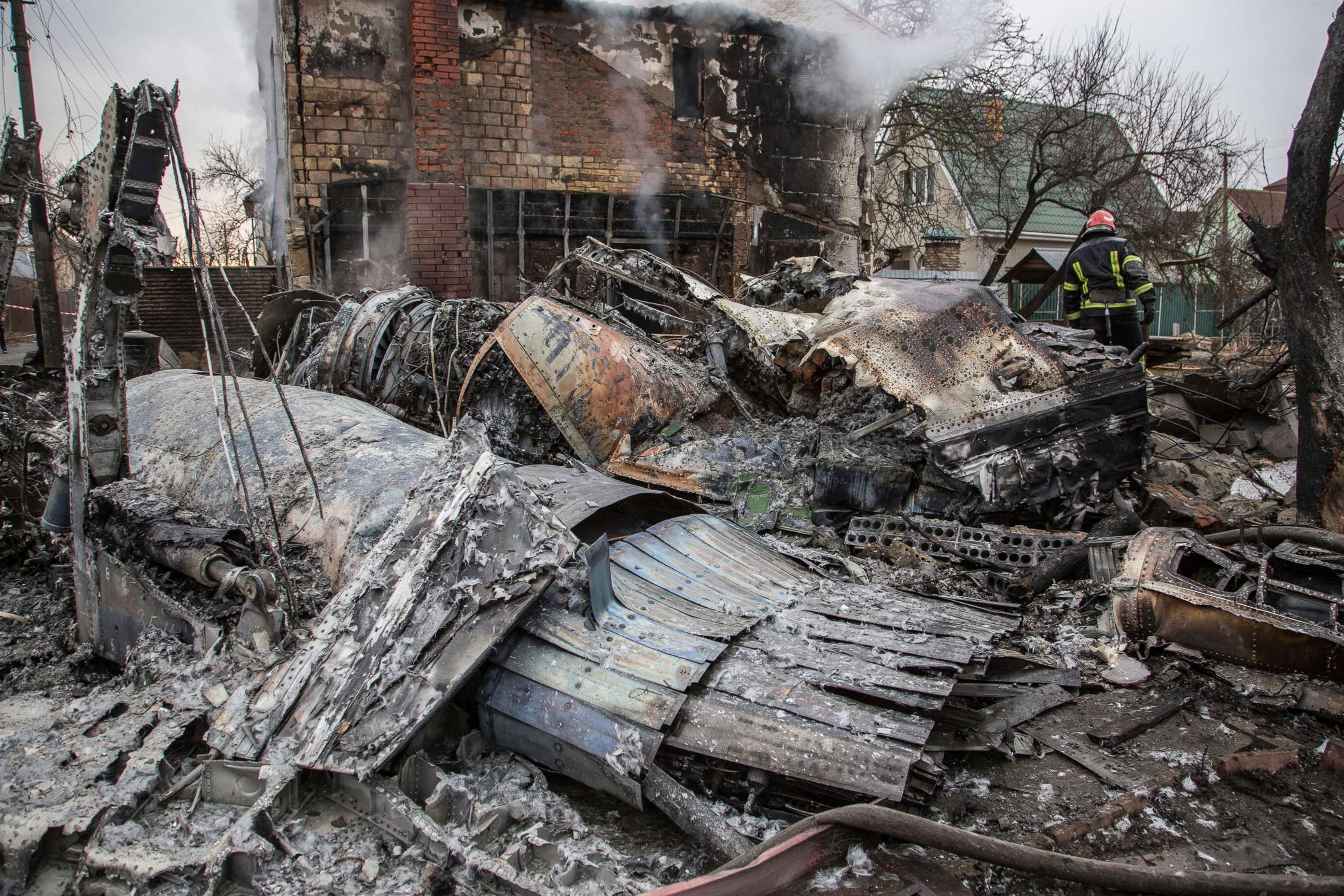 PHOTO: A Ukrainian firefighter walks between fragments of a downed aircraft seen in in Kyiv, Ukraine, Friday, Feb. 25, 2022.