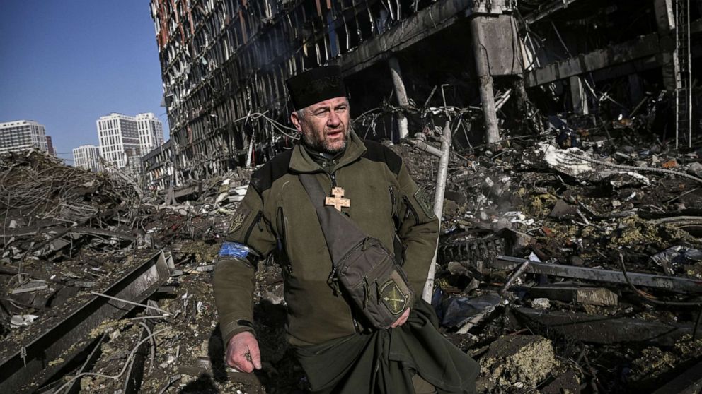 PHOTO: Ukraine army Chaplain Mikola Madenski walks through debris outside the destroyed Retroville shopping mall in a residential district, after a Russian attack on the Ukranian capital Kyiv on March 21, 2022.