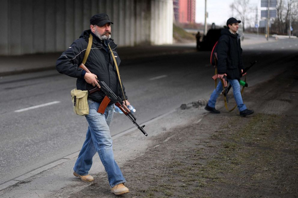 PHOTO: Volunteers, one holding an AK-47 rifle, protect a main road leading into Kyiv, Ukraine on Feb. 25, 2022.