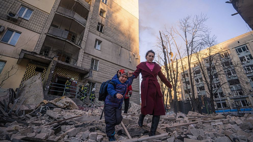 PHOTO: A woman with a child evacuates from a residential building damaged by shelling, as Russia's attack on Ukraine continues, in Kyiv, Ukraine, in this handout picture released March 16, 2022.