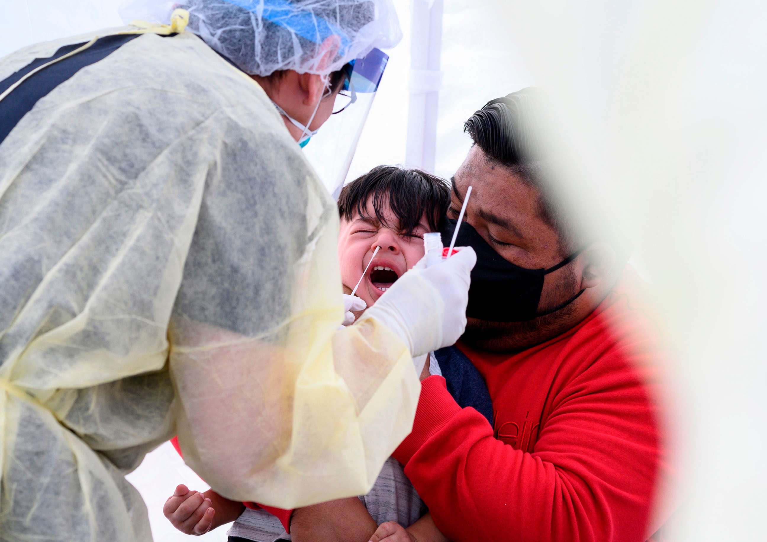 PHOTO: Jose Vatres holds his son Aidin as nurse practitioner Alexander Panis takes a nasal swab sample for COVID-19 at a mobile testing station in a public school parking area in Compton, Calif., April 28, 2020.