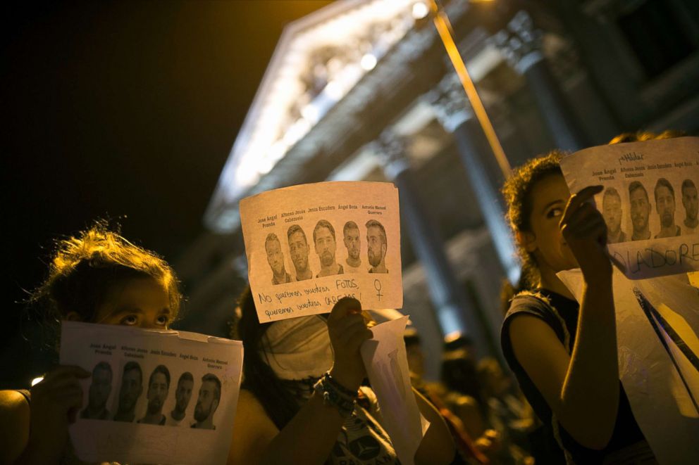 PHOTO: Women, some holding photographs of the five men known as "La Manada" or "The Pack" and reading: "Rapists" and "We don't want your photos but your heads", march outside the Spanish parliament during a protest in Madrid, April 26, 2018. 