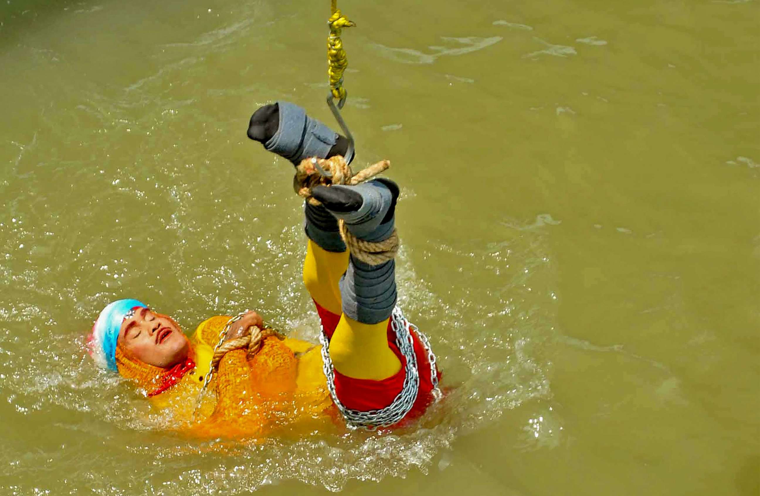 PHOTO:Indian stuntman Chanchal Lahiri, known by his stage name "Jadugar Mandrake", is lowered into the Ganges river, while tied up with steel chains and ropes, in Kolkata, June 16, 2019. 