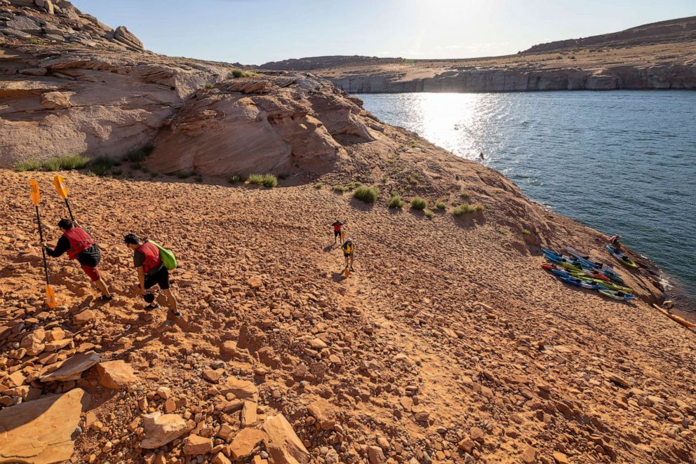 PHOTO: Kayakers ascend a steep and growing embankment between the unusable Antelope Point boat ramp and the water as the level of Lake Powell continues to drop on September 3, 2022 near Page, Arizona.