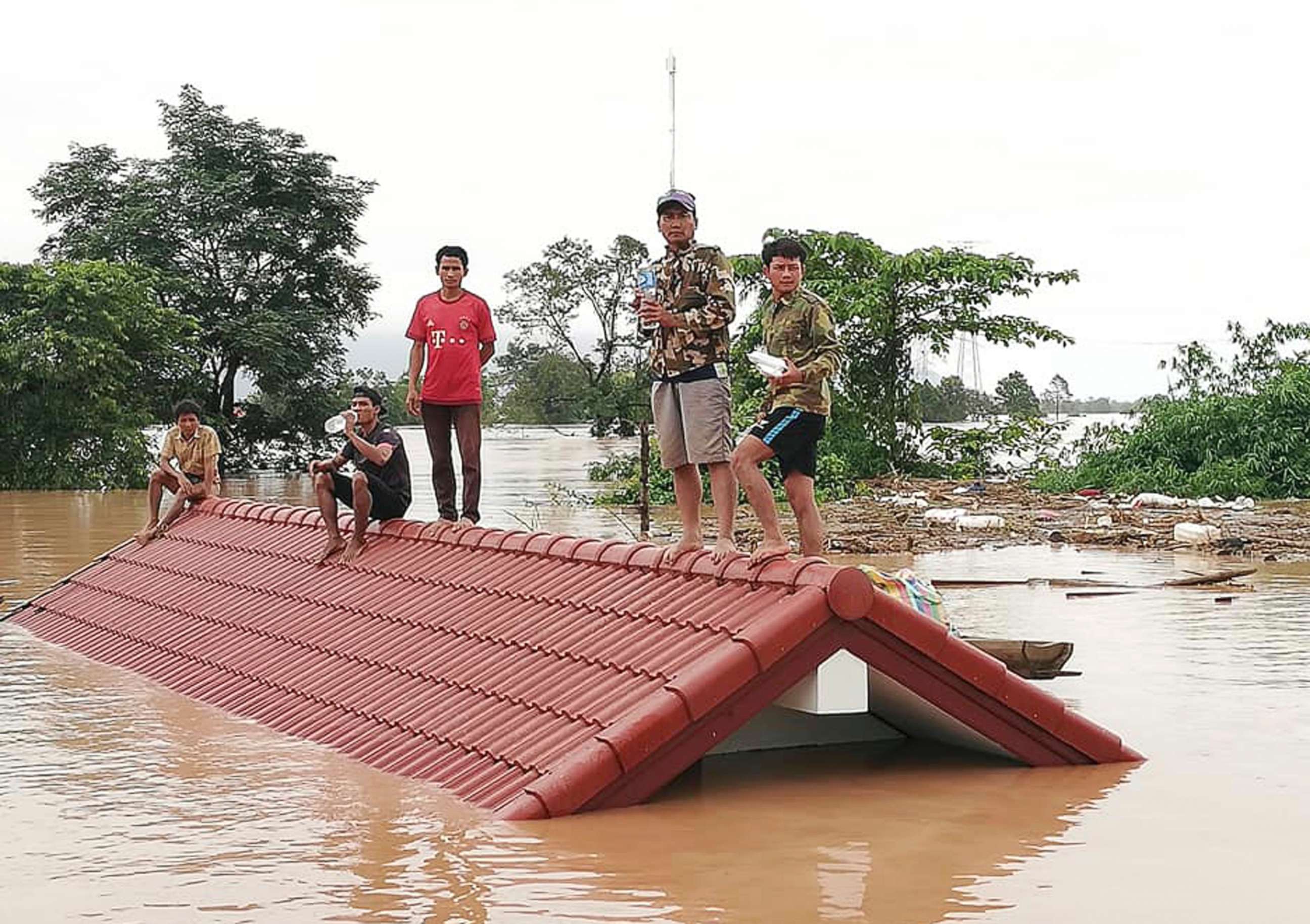 PHOTO: Villagers take refuge on a rooftop above flood waters from a collapsed dam in the Attapeu district of southeastern Laos, July 24, 2018.