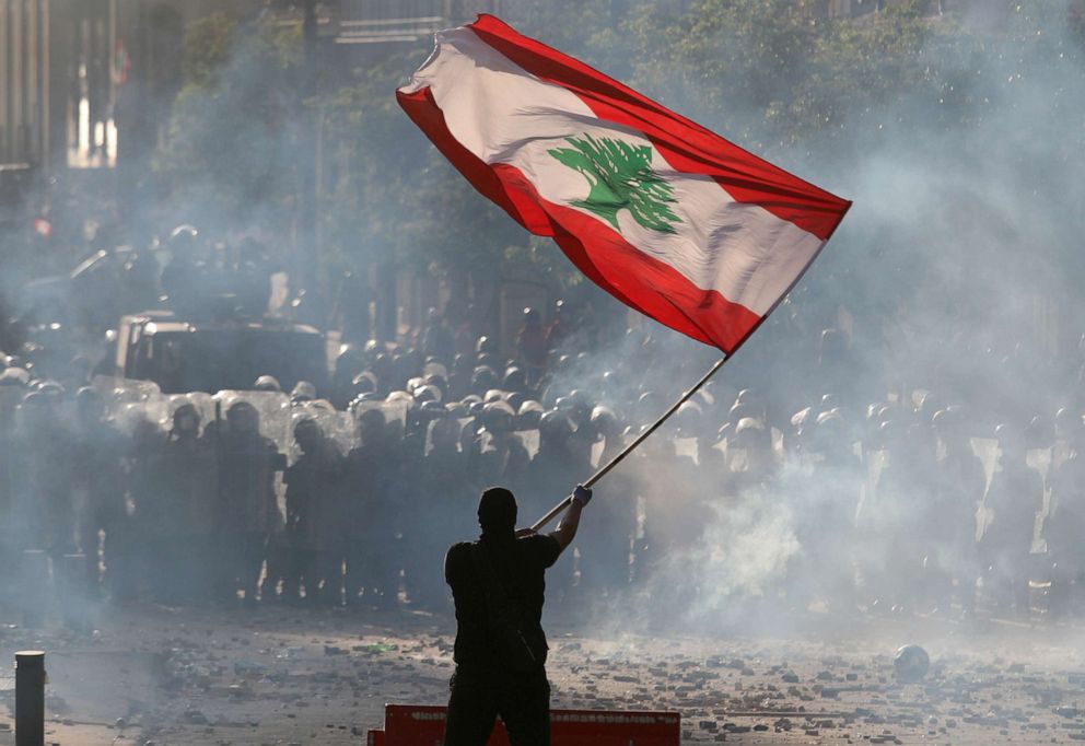 PHOTO: A demonstrator waves the Lebanese flag in front of riot police during a protest in Beirut, Lebanon, Aug. 8, 2020. 