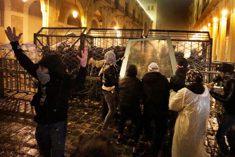 PHOTO: Anti-government protesters throw a glass panel against the riot police who are standing behind barriers defense, during ongoing protests against the political elites who have ruled the country for decades, in Beirut, Jan. 19, 2020.