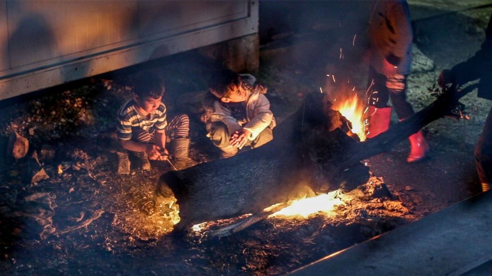  In Lesbos Moria refugee camp, children gather around fires to keep warm.