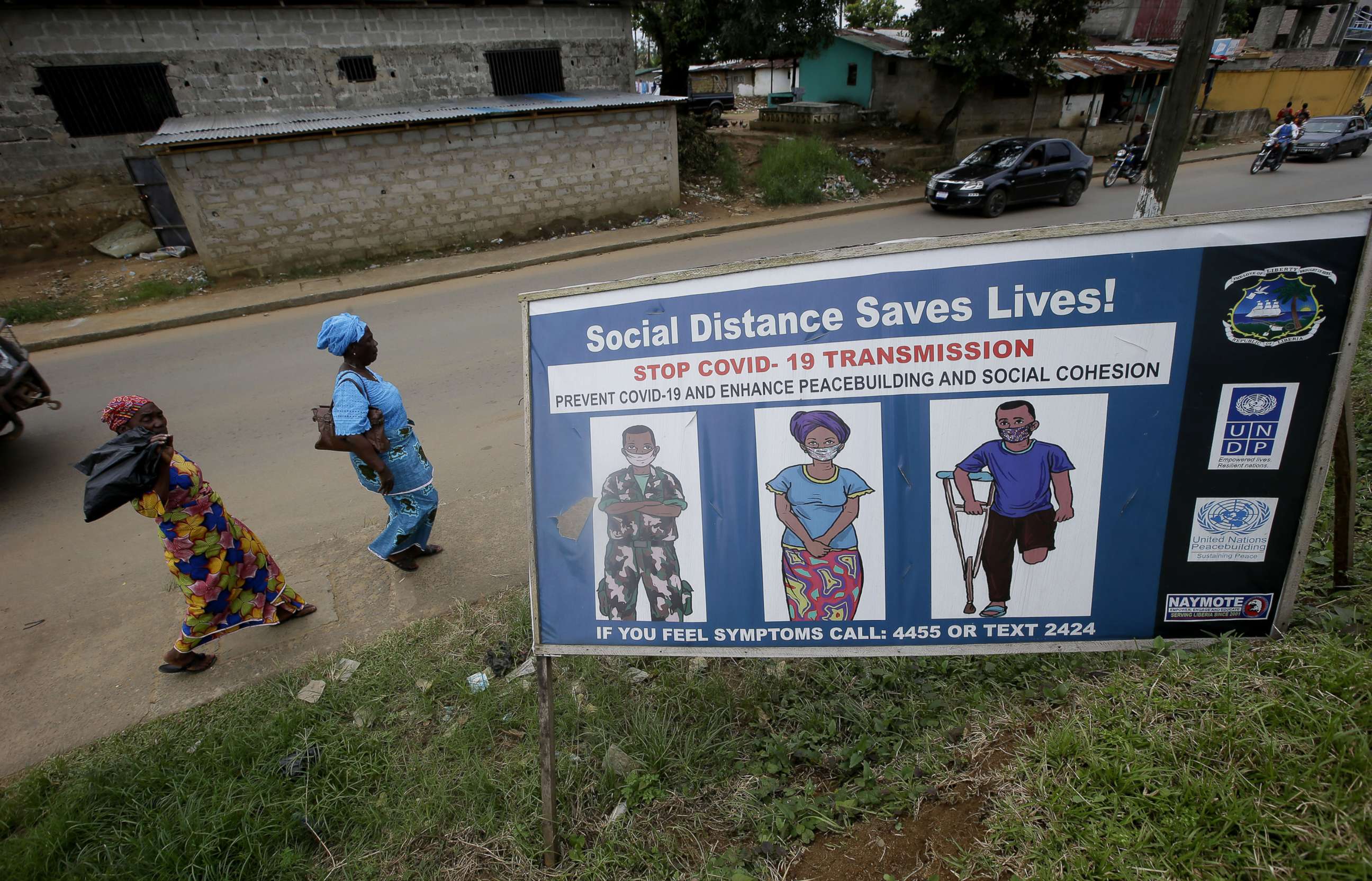 PHOTO: People walk past a billboard with coronavirus awareness campaign messages on a busy roadside in Monrovia, Liberia, Oct. 18, 2020.