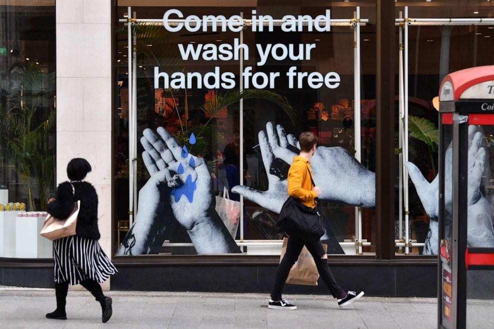 PHOTO: Pedestrians pass a cosmetics shop advertising free hand washing facilities in store in Liverpool, England, March 11, 2020.