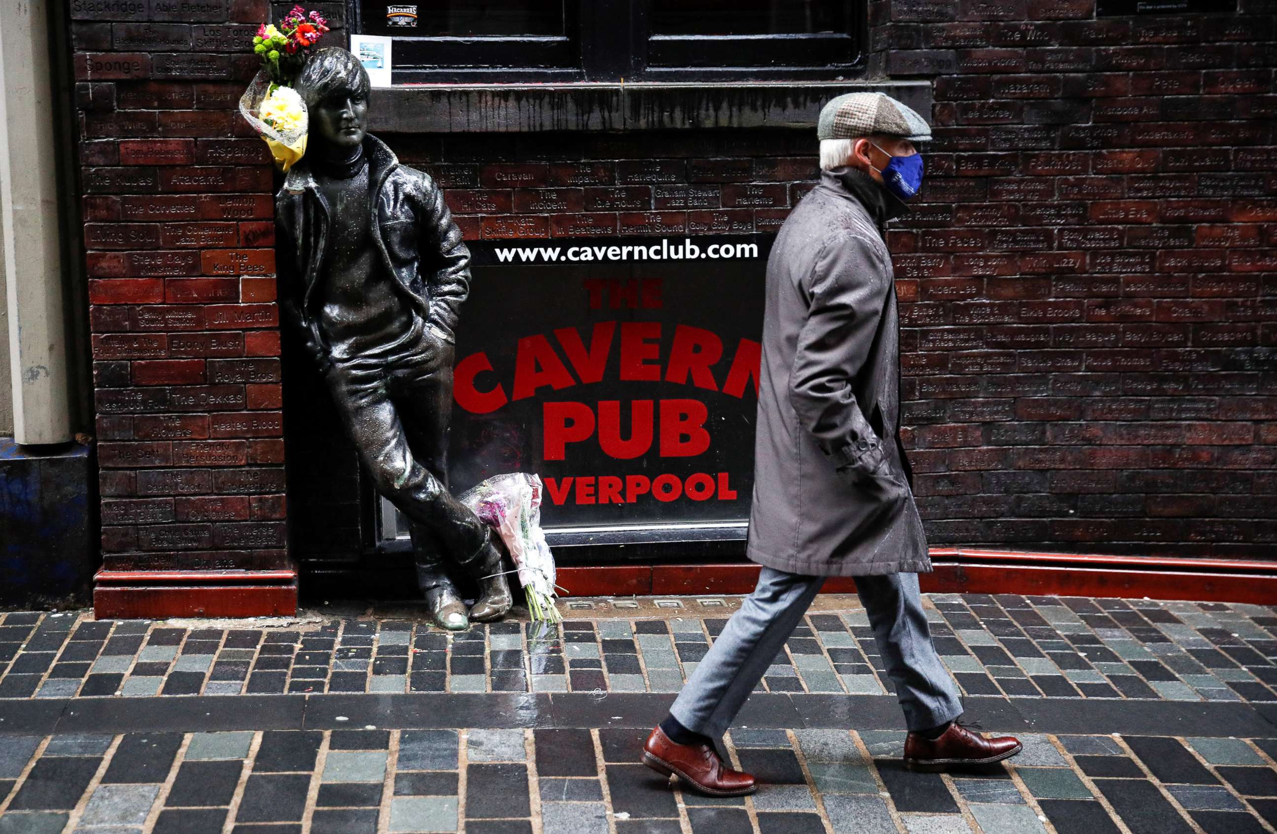 PHOTO: A man wearing a face mask walks past John Lennon statue amid the coronavirus outbreak in Liverpool, Britain, Oct. 12, 2020. 