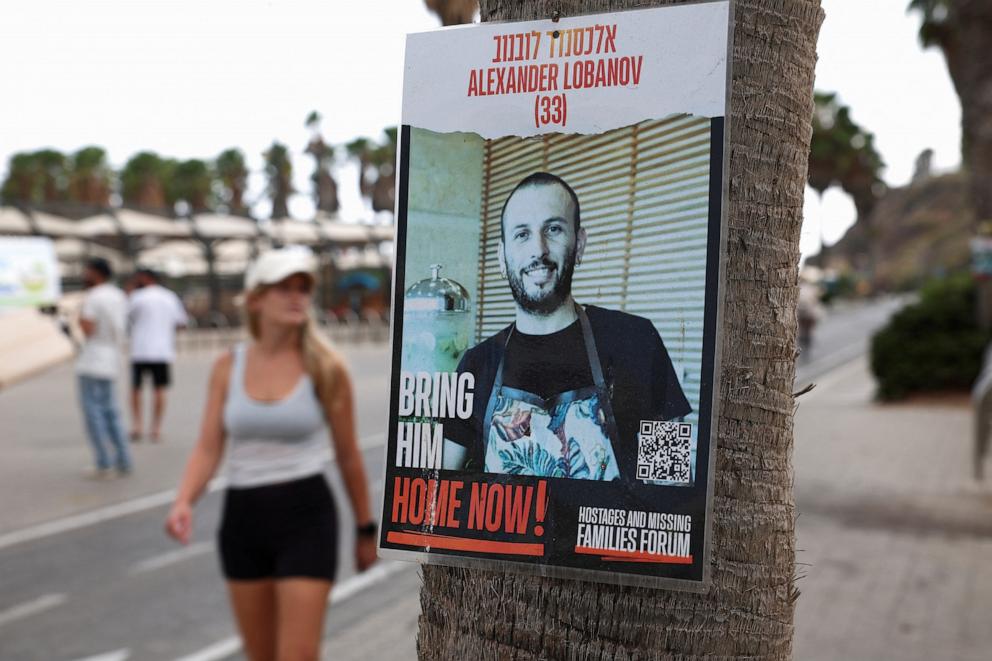 PHOTO: A woman walks near a poster showing Alexander Lobanov, who was taken hostage by Hamas during the Oct. 7 attacks, and whose body has been recovered from a tunnel in the Rafah area of the Gaza Strip, in Tel Aviv, Israel Sept. 1, 2024.