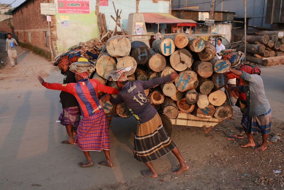 PHOTO: Laborers push a vehicle loaded with wood logs in Dhaka, Bangladesh on Nov. 22, 2020.