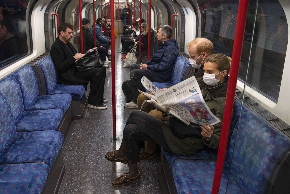 PHOTO: A couple rides the Central Line Tube wearing protective face masks while reading a newspaper, March 19, 2020 in London, England.