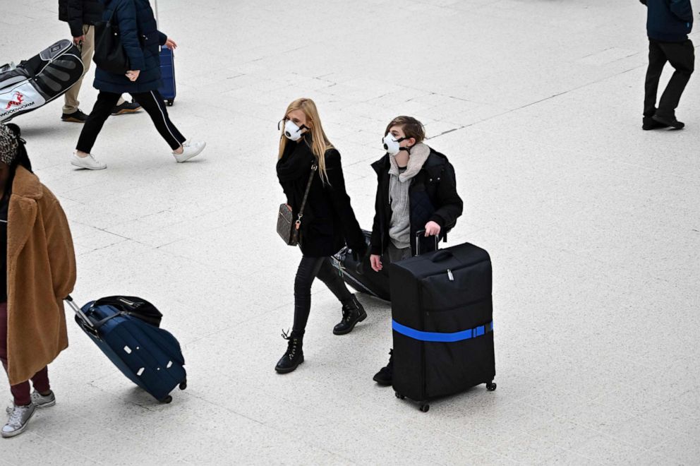 PHOTO: Travelers wearing protective face masks pull their suitcases while walking across the concourse at London Victoria train station in central London, U.K., on March 3, 2020.