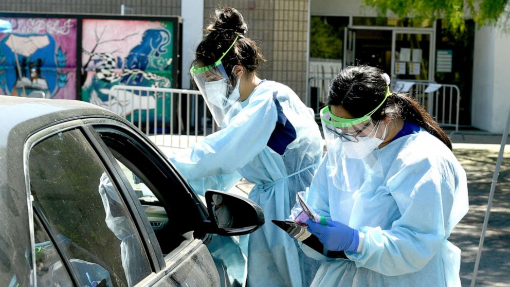 PHOTO: Mend Urgent Care workers wearing personal protective equipment (PPE) perform drive-up COVID-19 testing at Central City Value High School on July 31, 2020, in Los Angeles.