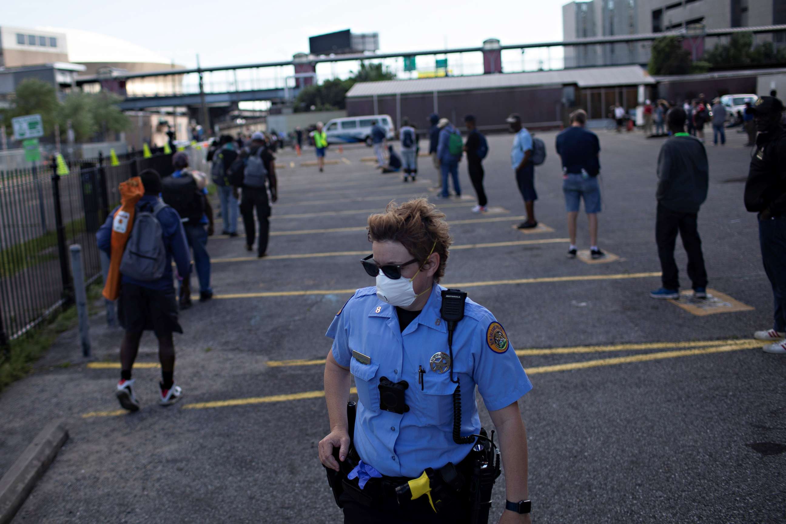 PHOTO: New Orleans police officer Deserie Broussard ensures people maintain social distancing by remaining six feet apart, as meals are distributed at the Lantern Light Ministry at the Rebuild Center, in New Orleans, March 31, 2020.